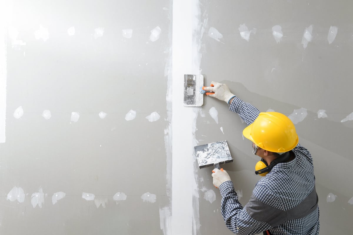 Craftsman plastering and finishing an interior wall during a home repair