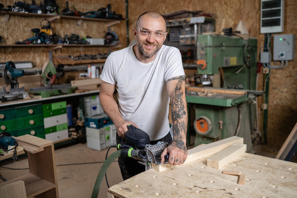 Carpenter using a power planer on a piece of wood in a workshop