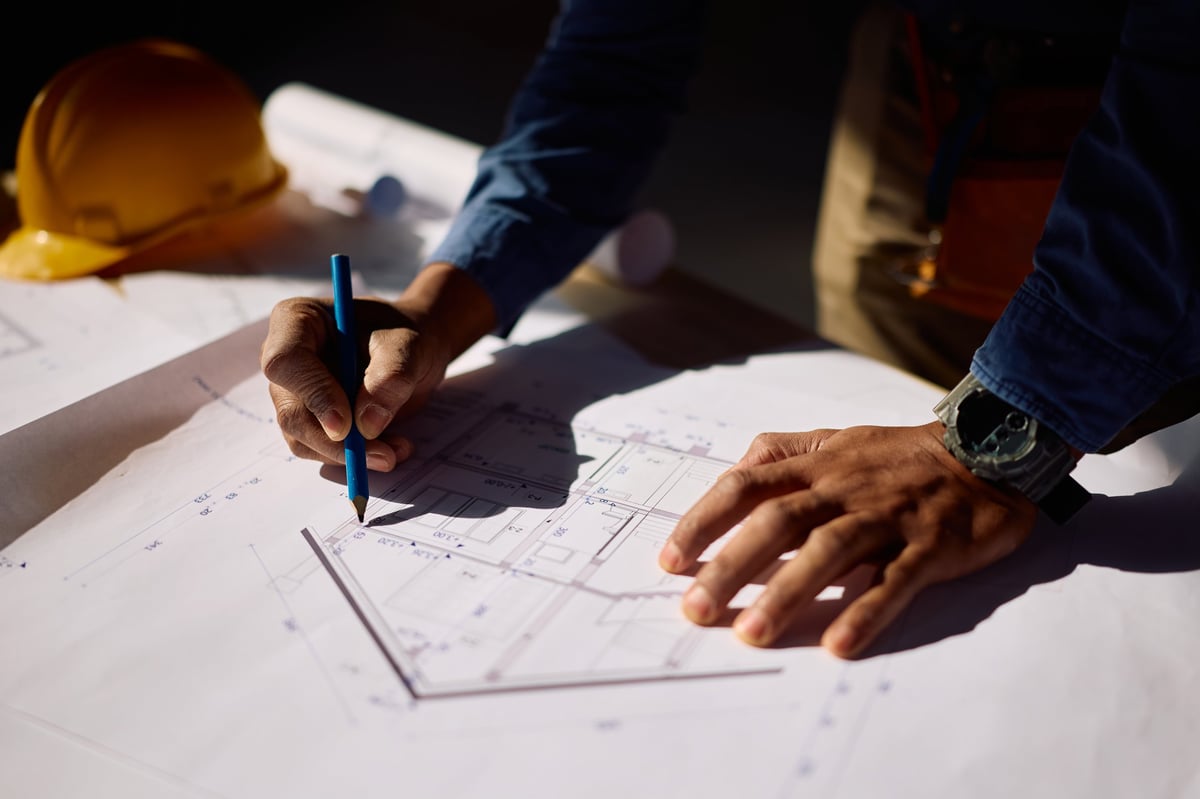 Two construction professionals reviewing plans inside a building under construction.