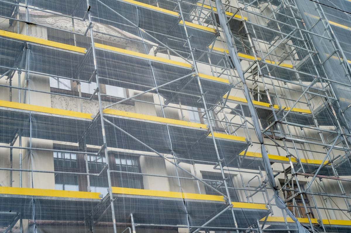Scaffolding and protective netting staged against a building elevation during facade access work
