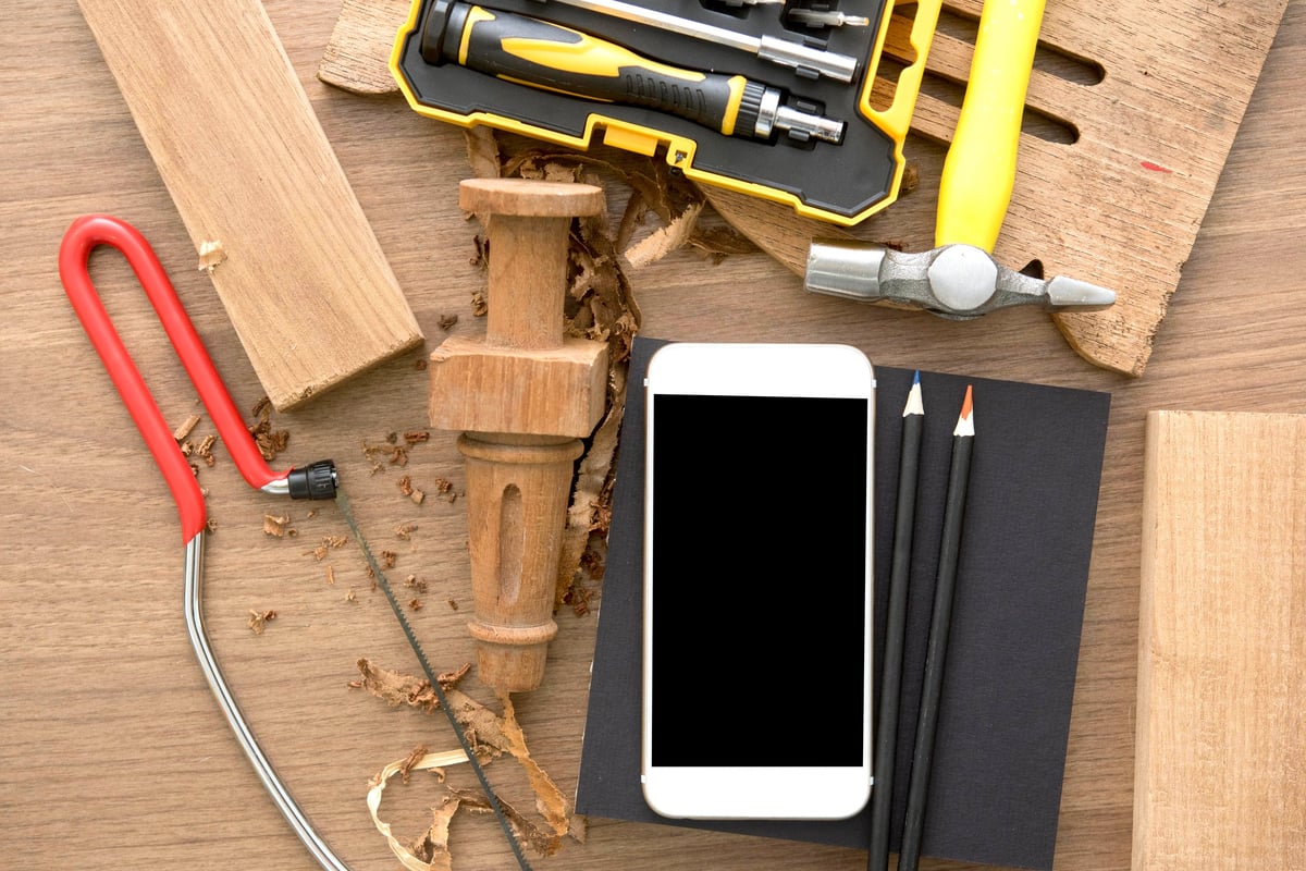 Tape measure, woodworking tools, and a clipboard on a workshop bench.