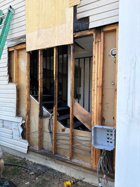 House exterior with wooden door frames and plywood sheets covering windows during renovation or repair