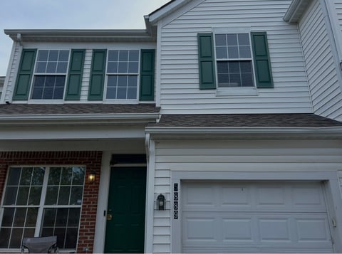 Darby Park residence in its original condition, with green shutters, a green entrance door, and weathered white wood trim.