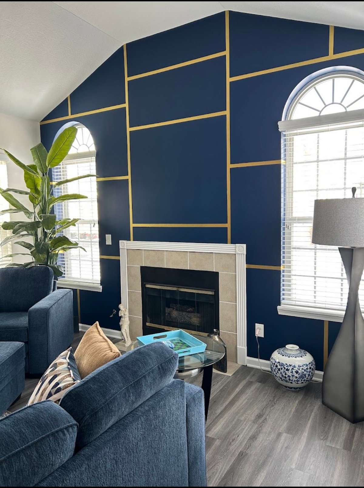 Living room renovation for Arlene H. in Newark, Ohio, featuring a navy fireplace wall with gold geometric detailing and arched windows.
